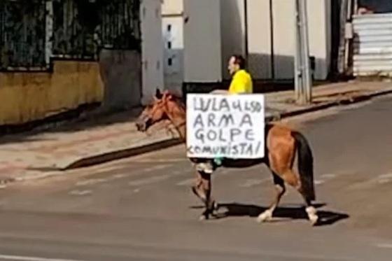 O advogado foi visto andando a cavalo e carregando uma placa com os dizeres: “Lula arma golpe comunista”