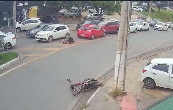 Imagens da câmera de segurança de um estabelecimento mostram o momento que a moto cai para um lado, e o motociclista é arrastado pelo carro