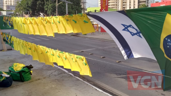 Vendedor de bandeiras acompanha ex-presidente Bolsonaro, vendendo bandeiras do Brasil e de Israel pelo país