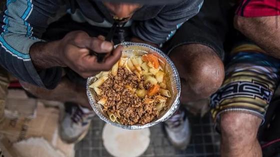 Movimentos sociais organizam "banquetaço" contra proibição de distribuição de marmitas em Cuiabá.